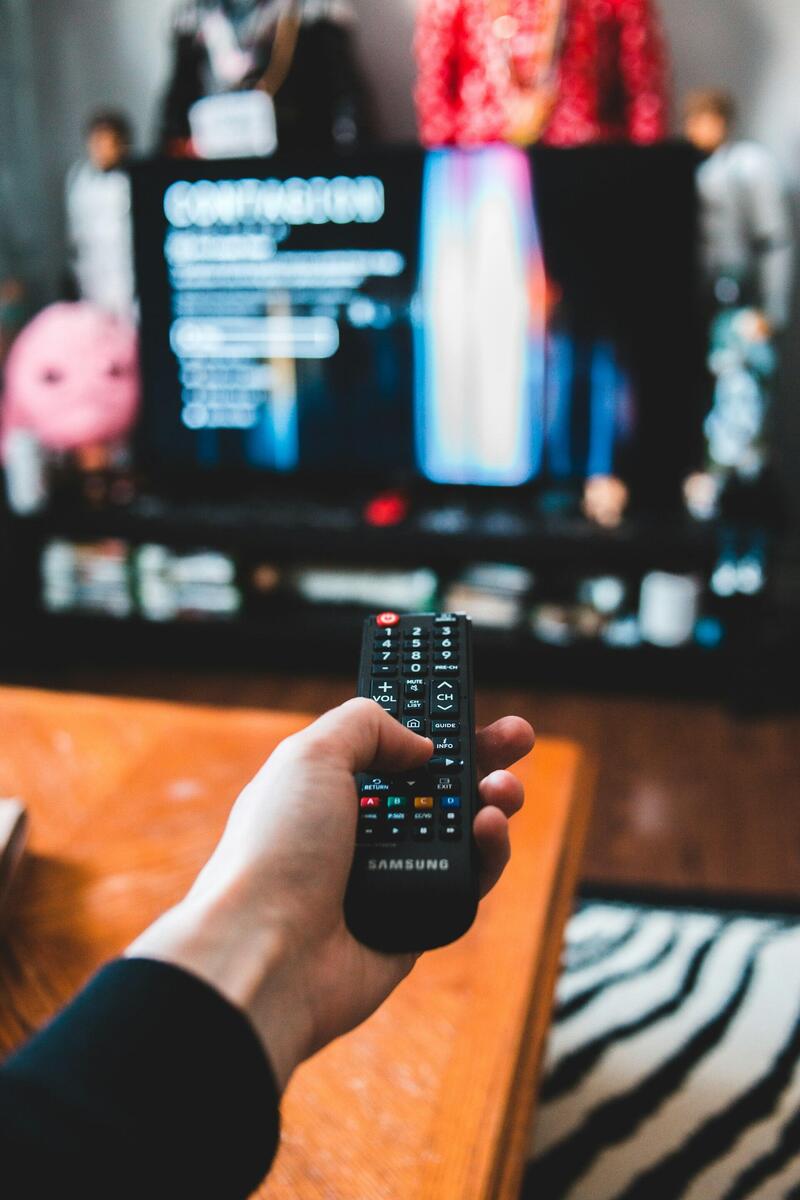 Stop IPTV buffering — proven fixes for smooth streaming Person using a remote control with a smart TV displaying streaming content in a living room